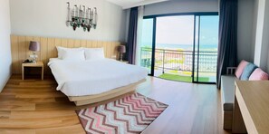 Quarto de hotel moderno com uma cama grande, vista para o mar, varanda e um elemento decorativo na parede.