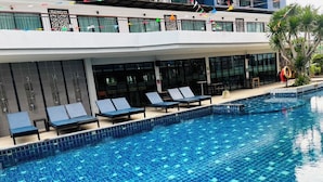 Ein Swimmingpool mit Liegestühlen und ein modernes Gebäude mit großen Fenstern.
