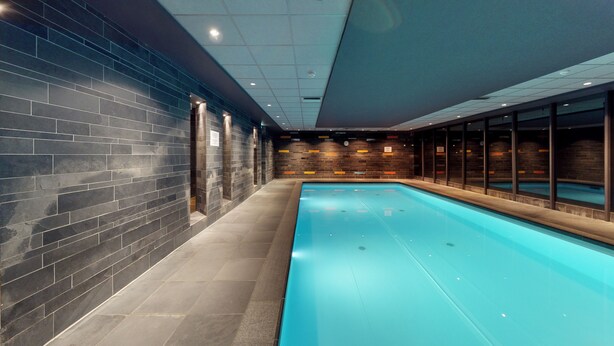 A swimming pool with tiled walls and a tiled floor, surrounded by windows. - Unwind in Zeist with On-site Pool, Dining, Free Parking, and a Peaceful Ambiance (Zeist)