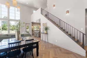 A spacious living area with a dining table, chairs, and a staircase. - New Zion cabin with hot tub, sauna, cold plunge @ Zion Knotty Pines (Mount carmel)