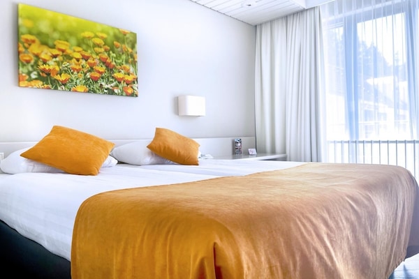 Unwind in a sunlit bed dressed in warm, cozy tones.