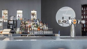 Uma área de bar com balcão, várias garrafas, copos e uma torneira.