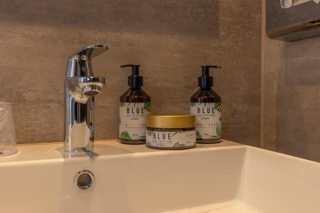 Een wastafel met een chromen kraan, twee flessen Blue Collection douchegel en een pot Blue Collection bodylotion.
