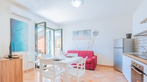 Eine kleine Küche mit Essbereich, einem roten Sofa und einem großen Fenster.