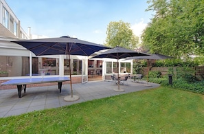 Une terrasse avec une table de ping-pong, des sièges d’extérieur et des parasols.