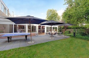Une terrasse avec une table de ping-pong, des sièges d’extérieur et des parasols.