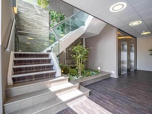 A modern interior with a staircase, glass railings, and a plant area.