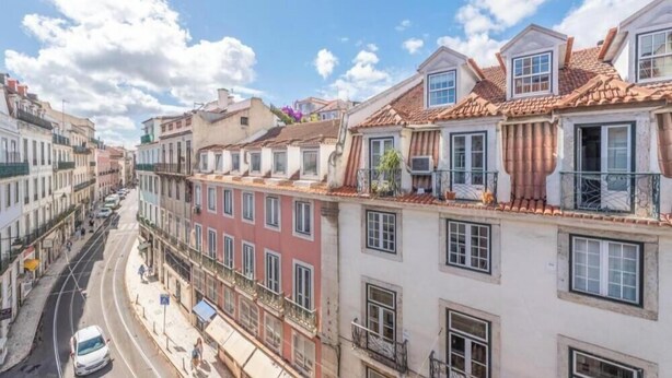 Filera d'edificis europeus tradicionals, amb diverses plantes, balcons i un cel serè.