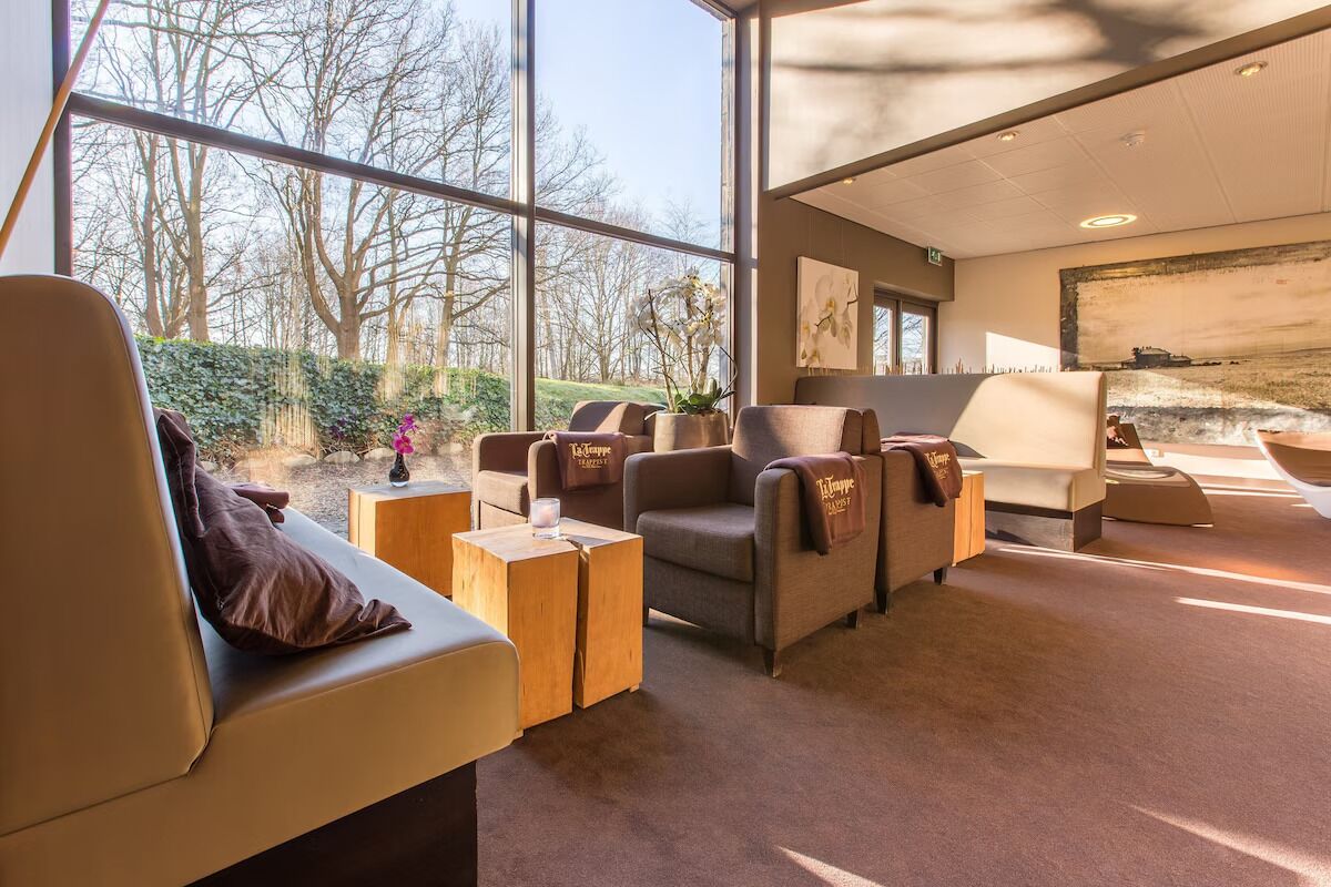 A modern interior with large windows, a sofa, armchairs, and a coffee table.