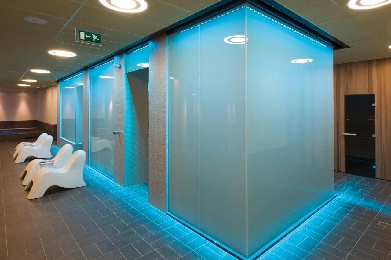Un espace spa moderne doté de fauteuils de massage, d’une paroi en verre et d’un éclairage encastré au plafond.