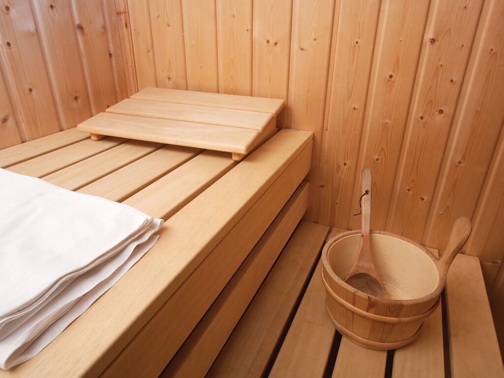 A wooden sauna bench with a towel and a wooden bucket with a ladle.