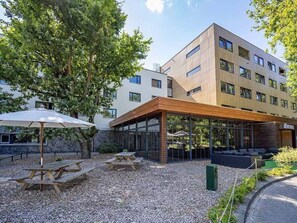 Un edificio moderno con un patio cubierto, mobiliario exterior y suelo de grava.