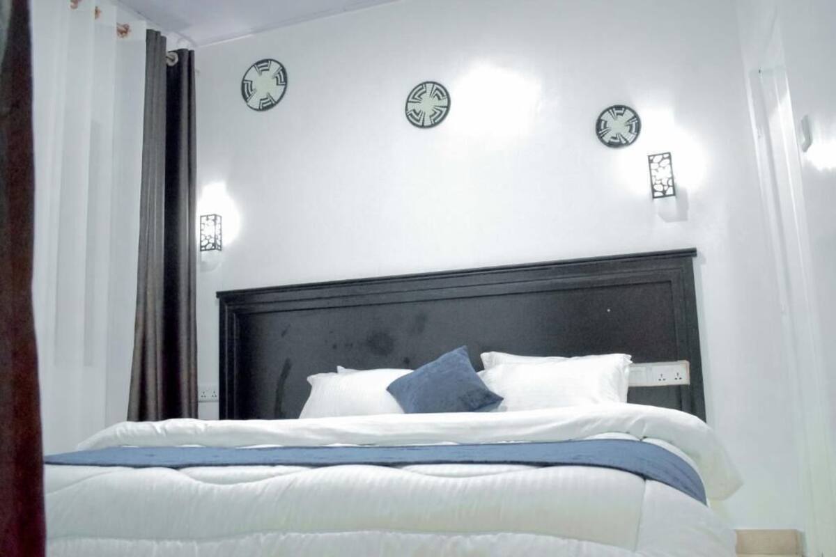 A bedroom with a bed, white walls, and three wall clocks.