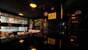 A dimly lit bar area with a reflective floor, wooden furniture, and decorative wall elements. - Inzozi Africa House B&B (Kigali)
