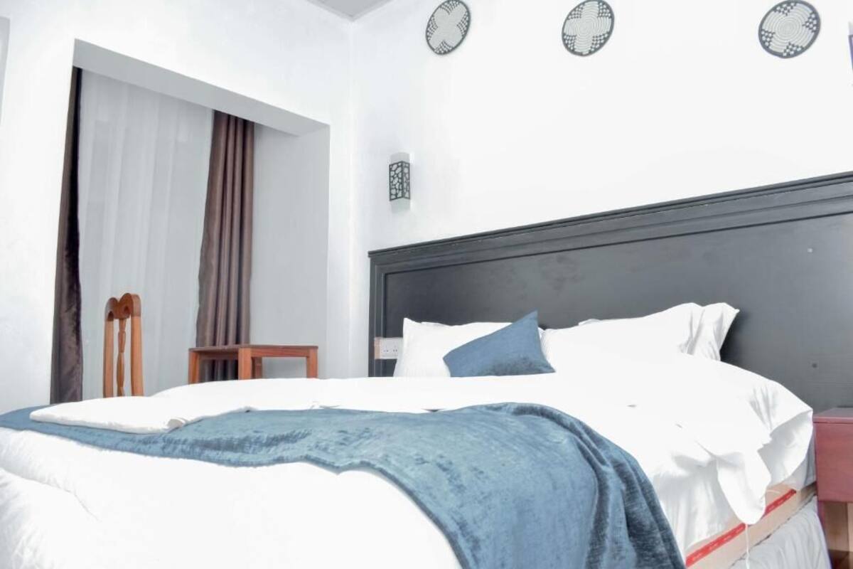A bedroom with a bed, a nightstand, a chair, and a wall-mounted lamp.