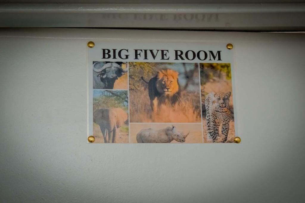 Eine Wand mit einem Plakat mit der Aufschrift 'BIG FIVE ROOM', das Fotos eines Büffels, eines Löwen, eines Leoparden, eines Nashorns und eines Elefanten zeigt.
