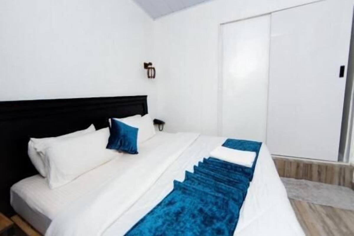 A bedroom with a bed, a nightstand, a wall-mounted light, and a wardrobe.