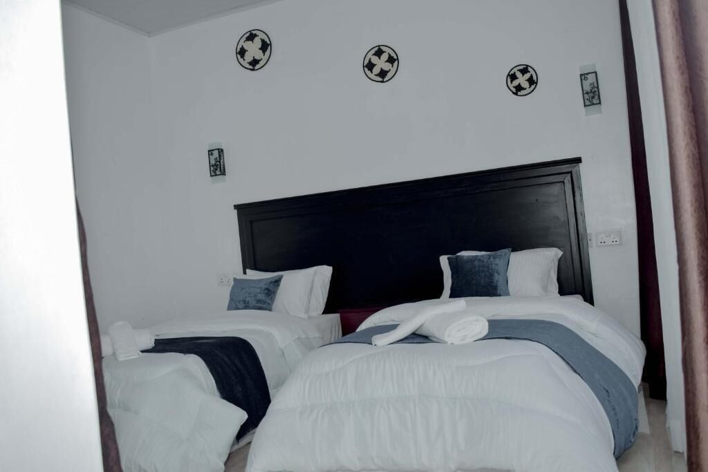 Une chambre d’hôtel avec deux lits, une tête de lit sombre et des autocollants décoratifs sur les murs.