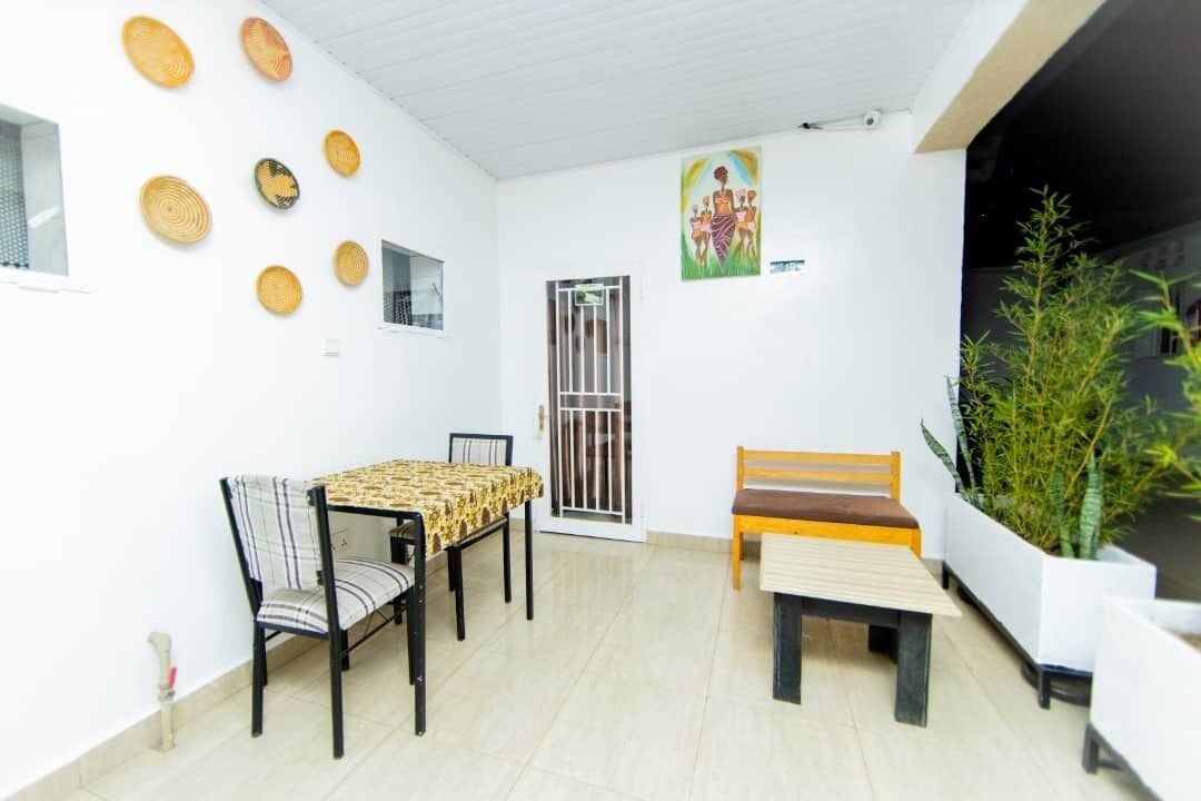 A dining area with a table and chairs, a bench, a potted plant, and a door with a metal gate.