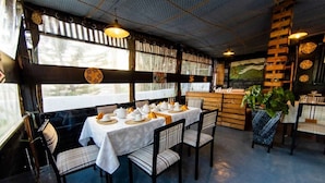 A restaurant with tables set for dining, chairs, a counter, and a large window with a view. - Inzozi Africa House B&B (Kigali)
