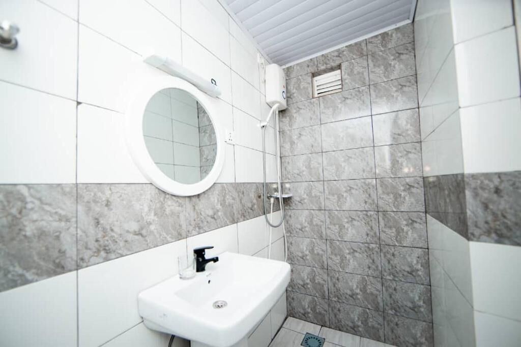 A bathroom with a white sink, a round mirror, and a shower area.