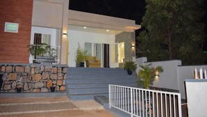A modern building with a stone facade, a set of stairs leading to a door, and potted plants. - Inzozi Africa House B&B (Kigali)
