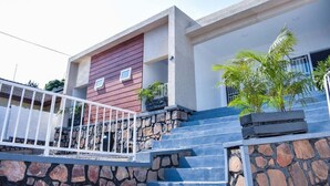 A modern building with a stone staircase, a red wall, and a white railing. - Inzozi Africa House B&B (Kigali)