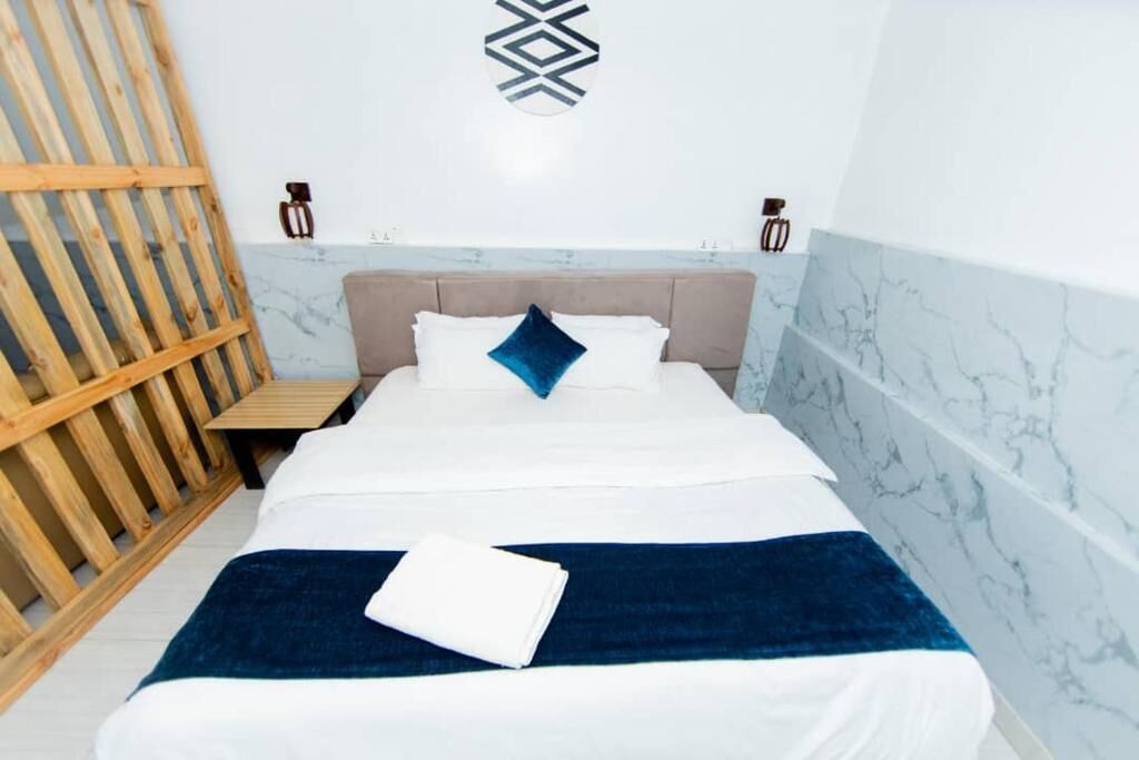 Habitación de hotel con cama, pared de listones de madera y paredes de mármol.
