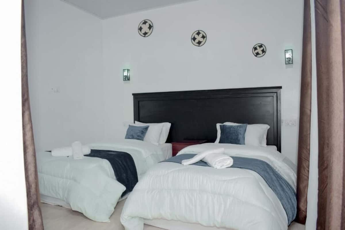 A hotel room with two beds, a dark headboard, and decorative wall plates.
