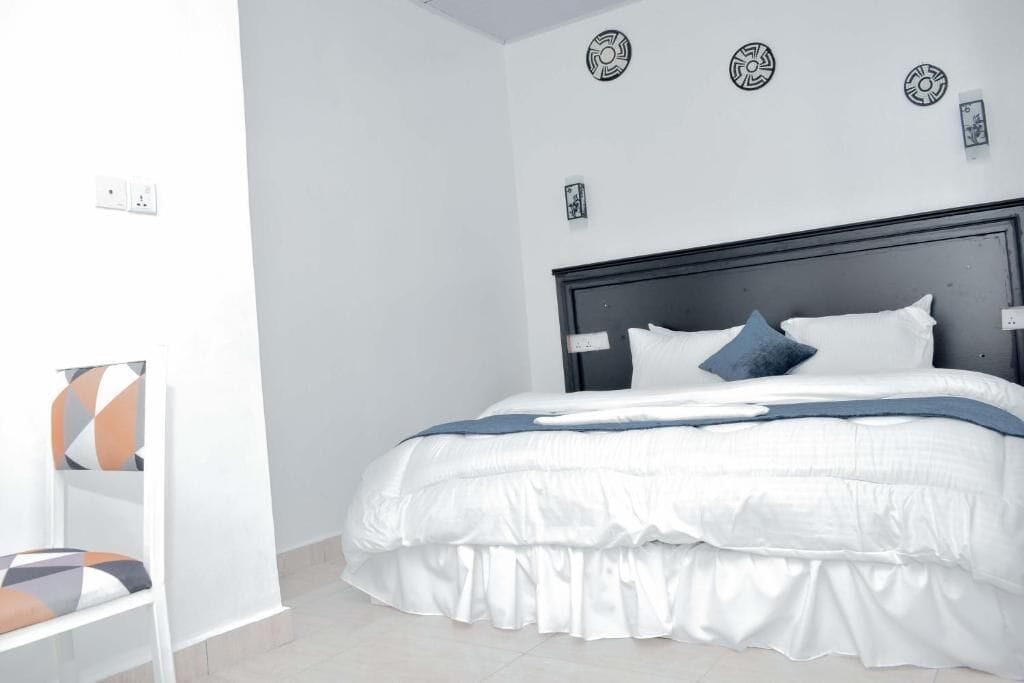 A bedroom with a bed, white walls, and a headboard.