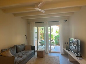 Un salon avec un canapé, un téléviseur et un ventilateur de plafond.