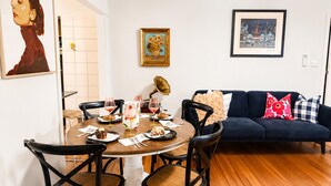 A dining area with a round table, chairs, and a dark blue sofa with patterned cushions. - Near St Kilda Beach Stay, Free Parking, Courtyard & Formula 1 (St Kilda)