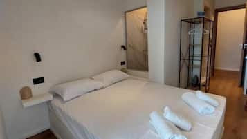 A modern bedroom with a large bed, a small bedside table, a mirror, and a walk-in closet.