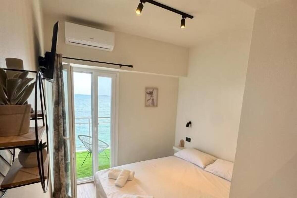 A bedroom with a bed, a window, a door, and a staircase.