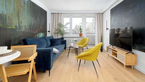 Ein modernes Wohnzimmer mit einer Couch, Sesseln, einem Fernseher und einem großen Gemälde an der Wand.