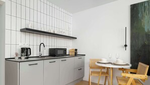 Eine moderne Küche mit weißen Schränken, einer schwarzen Arbeitsplatte und einem Essbereich mit einem runden Tisch und Holzstühlen.