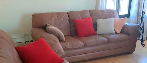 A living room with a brown leather sofa, a large mirror, and a floor lamp.