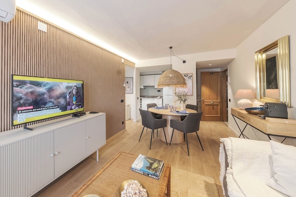 A modern living room with a TV, dining area, and a cozy seating space.