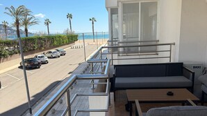 Un balcón con vista a un estacionamiento, una playa y palmeras.