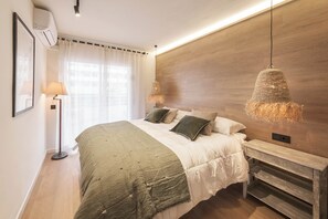 A bedroom with a bed, bedside tables, a lamp, and a hanging light fixture.