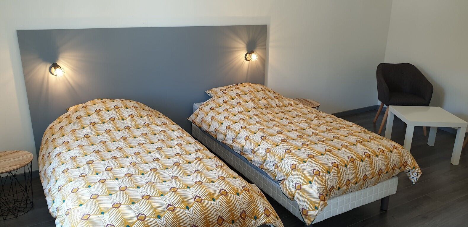 Een kamer met twee bedden, een kleine tafel en een stoel.