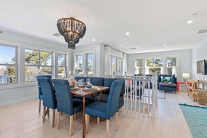 Ein geräumiger Essbereich mit Holztisch und blau gepolsterten Stühlen, großen Fenstern und einem Balkon mit Geländer.