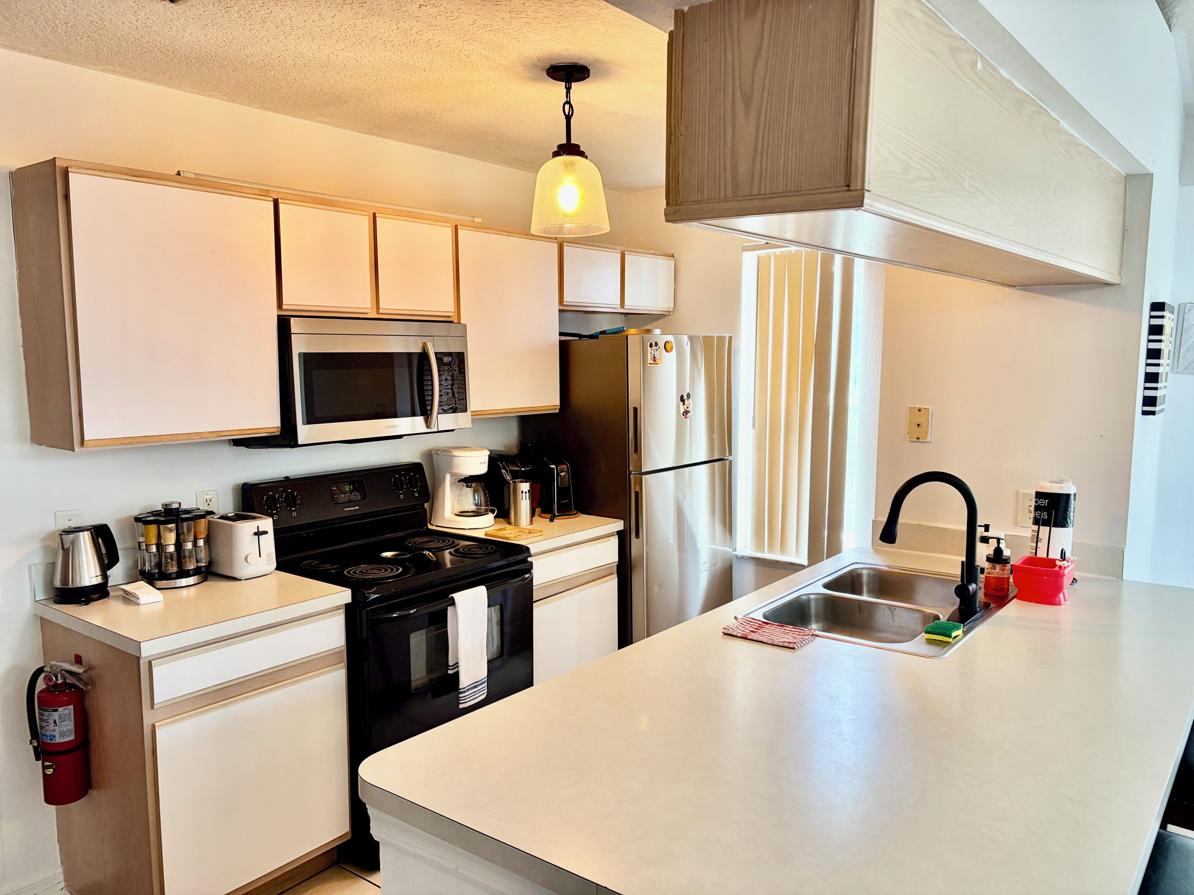Una cocina moderna con estufa, microondas, refrigerador y una isla grande con pileta.