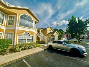A residential street with houses, a car, and a clear sky. - Grand Family Superior 3BR Condo near Disney (Four Corners)
