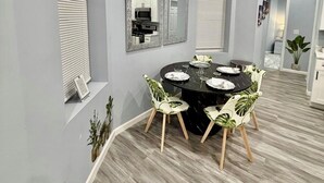 A dining area with a round table, chairs, and a window with blinds.