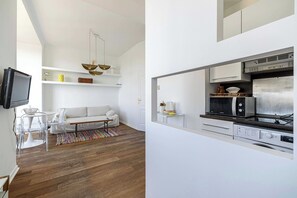 A modern living room with a sofa, TV, and a dining area with chairs. - Air-conditioned Seafront Apartment - Nice (Nice)
