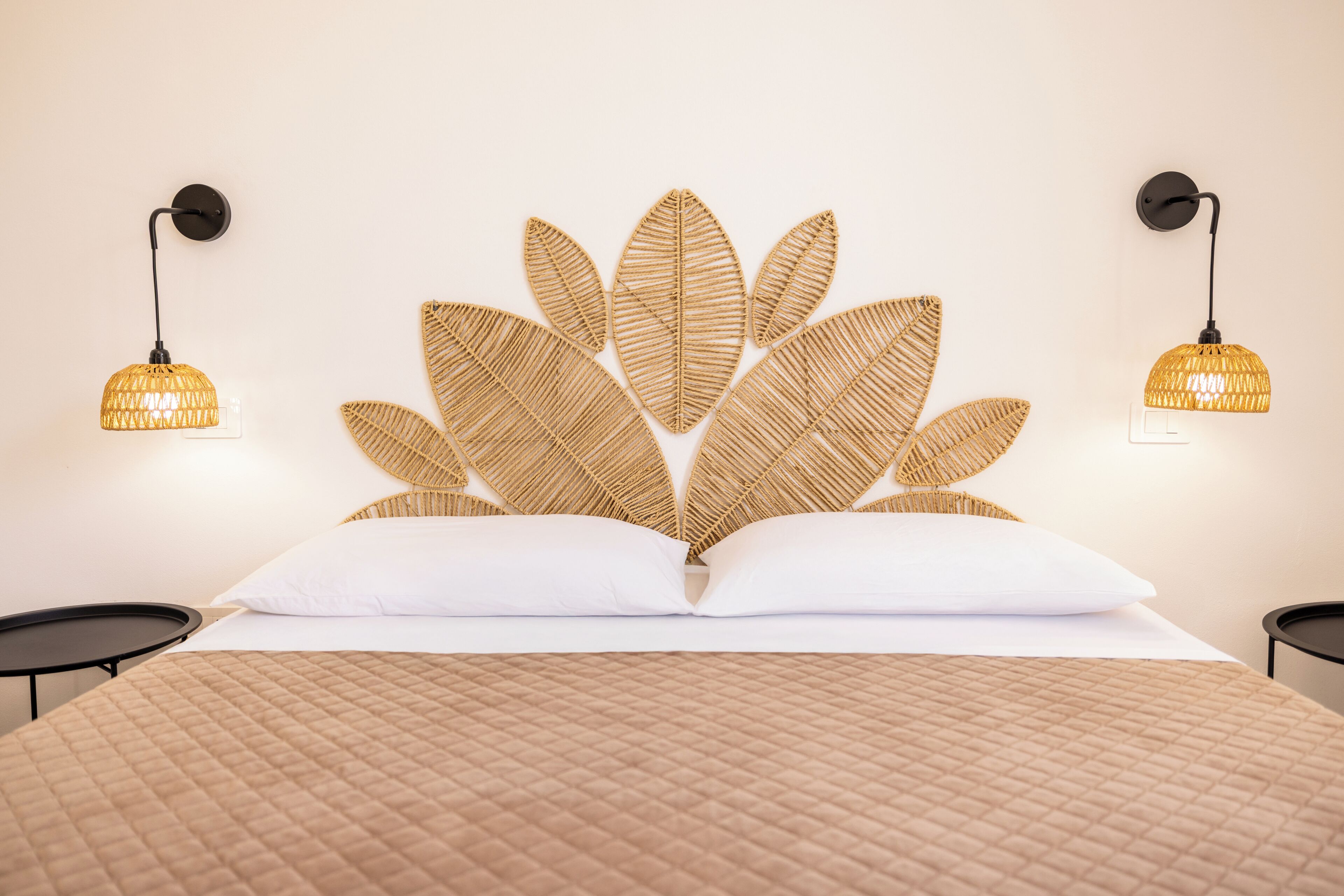 A bed with a textured headboard, two bedside lamps, and a quilted bedspread.