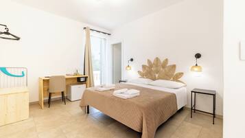 A hotel room with a bed, desk, chair, and a small table.