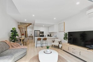 Eine moderne Wohnung mit Wohnzimmer, Küche, Essbereich und einer Treppe.