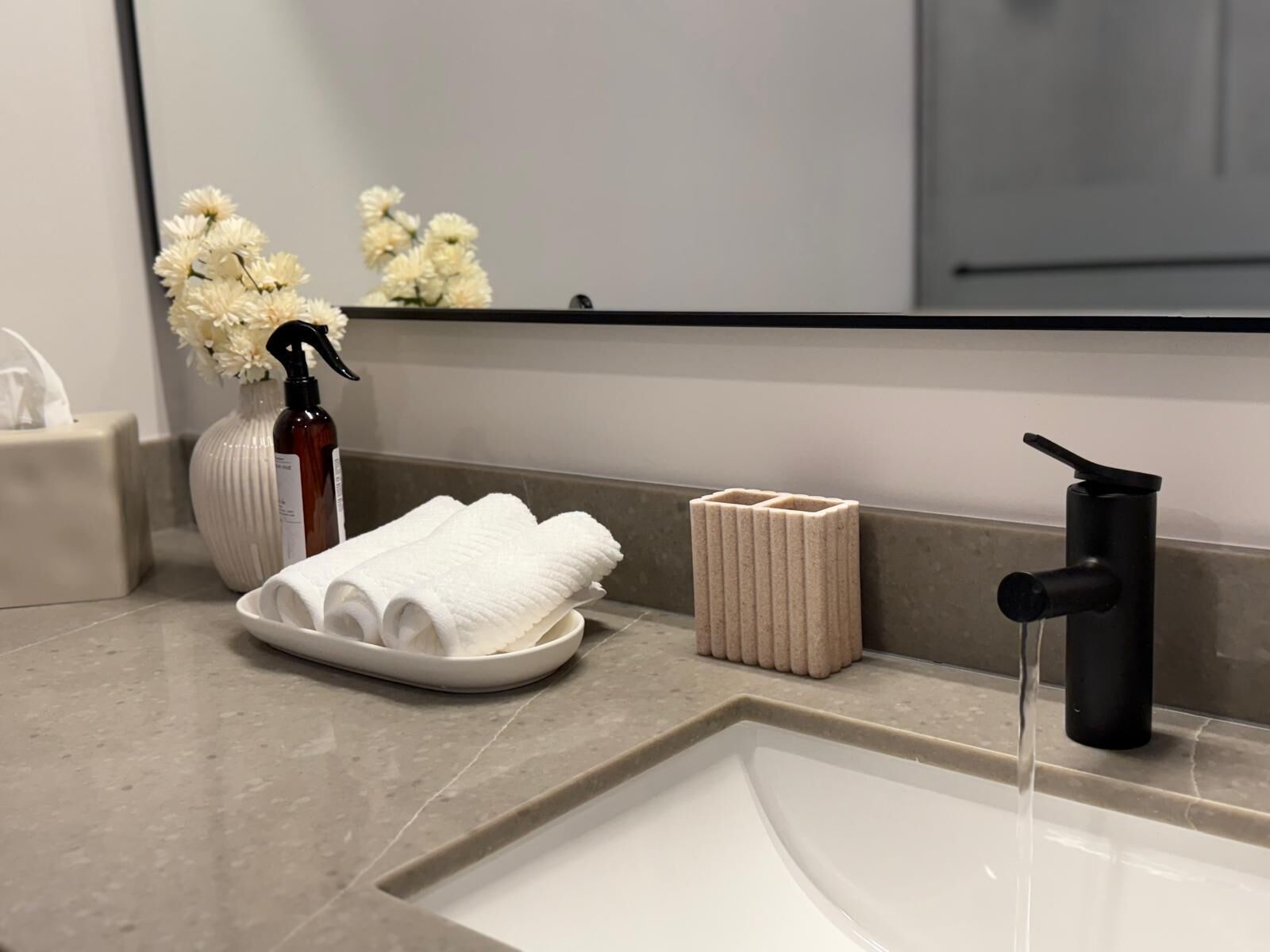 A bathroom with a sink, a mirror, a towel rack, and a bottle of hand sanitizer.